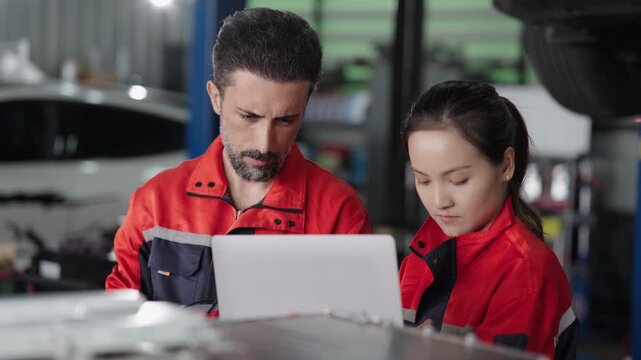 Red test probe is picked up beside a laptop as the mechanic prepares to test the electric car battery