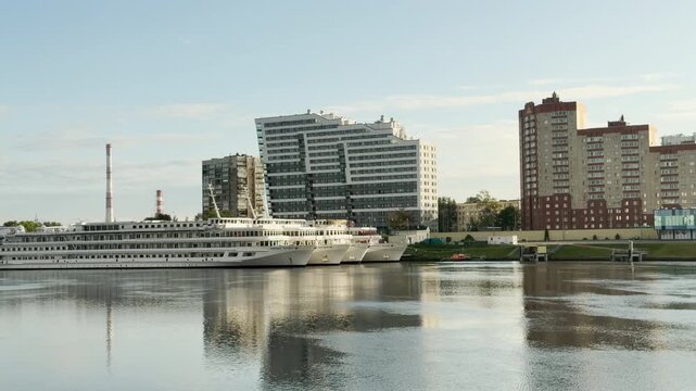 A majestic cruise ship moors peacefully along the calm Neva River. This lovely scene highlights the urban charm of Saint Petersburg.