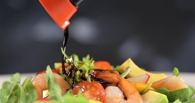 Soy sauce pouring onto fresh shrimp salad on black background slow motion 1000 fps