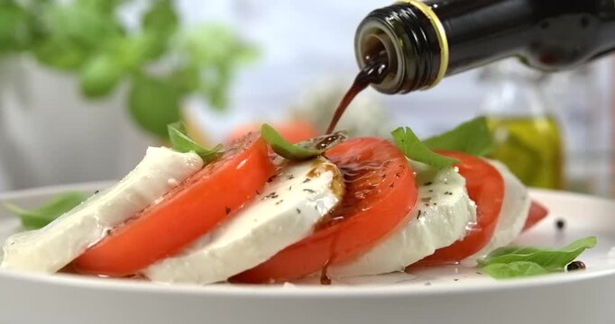 Balsamic vinegar pouring onto caprese salad on white kitchen background slow motion 1000 fps