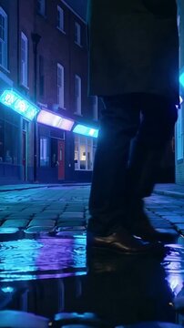 Vertical video: Left foot nearing puddle urging man in dark coat walking night cobbles, neon splash