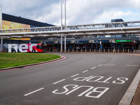Birmingham, UK - September 17th 2026: bus terminal at the entrance to the NEC exhibition centre with covered walkway, steel columns, glass doors, and parked coach under urban canopy