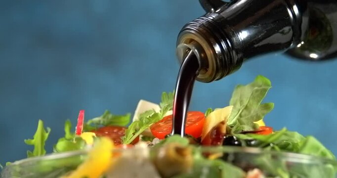 Balsamic sauce pouring over fresh vegetable salad slow motion 1000 fps