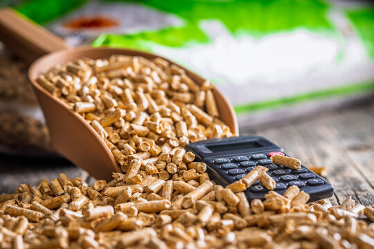 Wood Pellets And Calculator On Table Representing Biofuel Heating Costs And Renewable Energy Budgeting