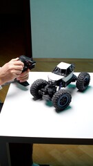 Person's hands holding a radio control transmitter, operating a remote control monster truck toy, highlighting hobbies, play, and modern entertainment © Aliaksandr