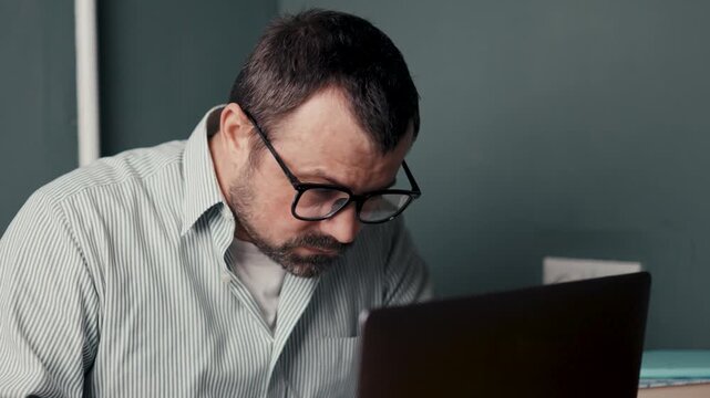 Exhausted man rubbing neck from muscle pain during late computer work