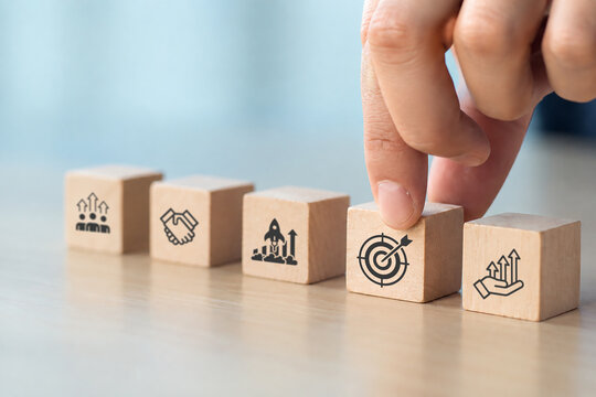 Business strategy concept. Wooden blocks with icons representing business strategy elements%3B teamwork  partnership  innovation and technology  target and growth. Business goal acheivement.