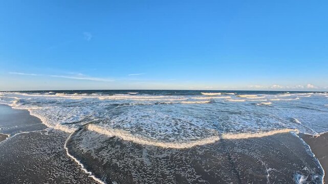 White foam retreats across wet sand on an Atlantic beach in 4K video.

