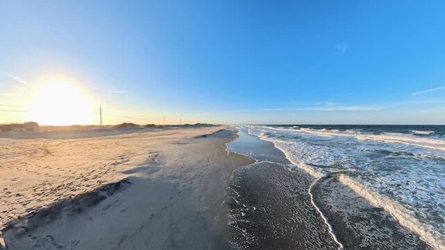 Low sunlight illuminates an Atlantic shoreline beside rolling surf in this 4K video
