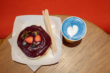 Cinnamon bun topped with berry glaze and fresh strawberries, served with blue matcha latte or lavender raf, cozy food styling with natural grain. high quality photo © Татьяна Швец