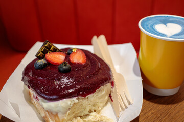 Cinnamon bun topped with berry glaze and fresh strawberries, served with blue matcha latte or lavender raf, cozy food styling with natural grain. high quality photo © Татьяна Швец
