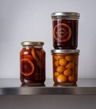 Jars of preserved fruits and vegetables on a metal shelf