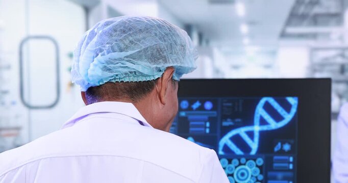 Rear view of a laboratory scientist in a hairnet studying dna data on a computer screen in a clean modern research lab