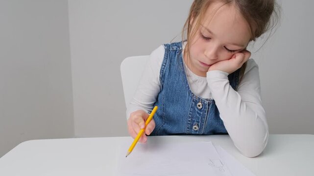 creative Child drawing on paper at a table in a simple indoor setting