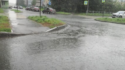 Fototapeta premium Puddles on the asphalt, rain falling, view from inside the car including the side mirror; a modern city in bad weather. drops of rain on the side window of the car water falls from the drivers windowb