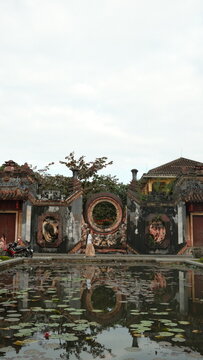 Traditional Asian temple wall with circular moon gate reflected in a lotus pond