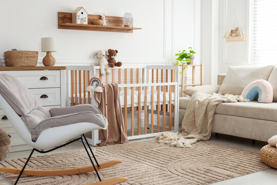 Stylish room with baby's crib and sofa. Interior design