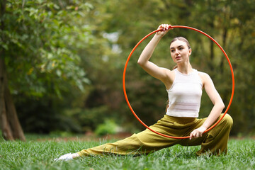 Athletic young woman posing with hula hoop in park, space for text © New Africa