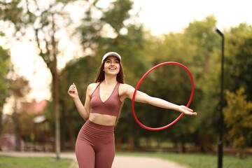 Athletic young woman exercising with hula hoop in park © New Africa