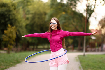 Athletic young woman exercising with hula hoop in park © New Africa