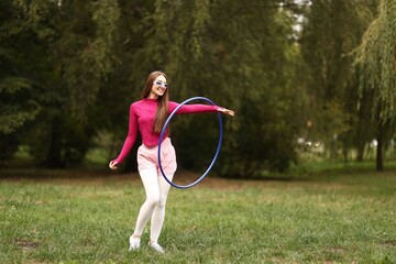 Athletic young woman exercising with hula hoop in park © New Africa