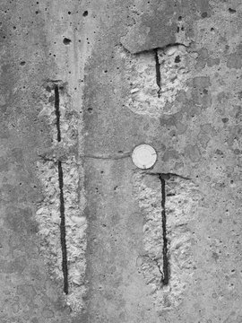  black and white close-up showing severe concrete spalling with exposed, rusted rebar steel reinforcement bars