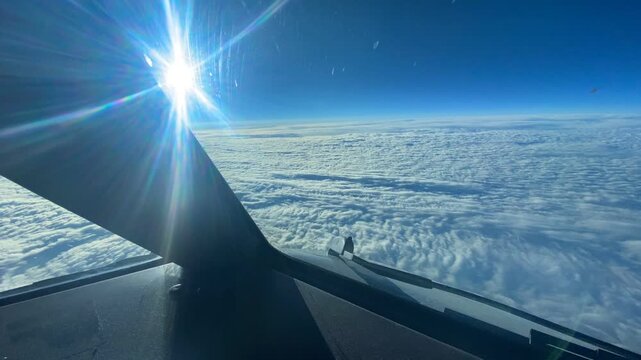 Airline pilot&rsquo;s point of view flying above a vast cloud layer toward brilliant sunlight, capturing a dramatic high-altitude aviation scene.