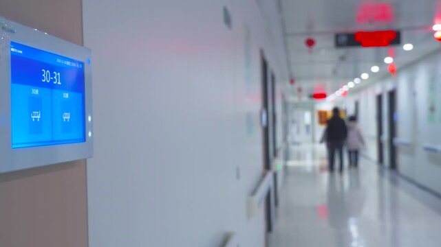 Modern Hospital Corridor with Digital Room Number Display and Blurred People Walking