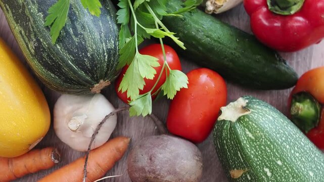 Fresh vegetables on a rustic wooden table at a sunny farm&mdash;countryside freshness and an organic lifestyle. Autumn harvest: zucchini, tomatoes, carrots, cucumbers, beets, and bell peppers.