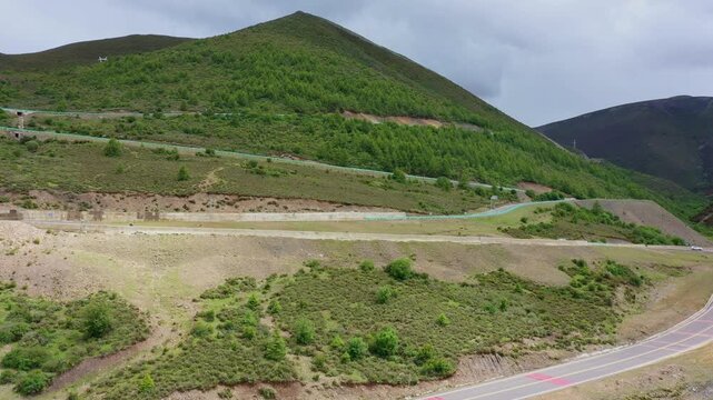 Winding Mountain Highway Through Green Forested Hills Under Cloudy Sky