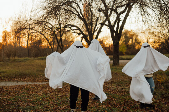 People wearing ghost costumes in autumn park