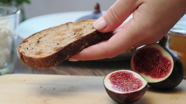 Toasted whole wheat bread with figs, ricotta (cream cheese),mint, honey served on white wooden cutting board. Healthy food concept.