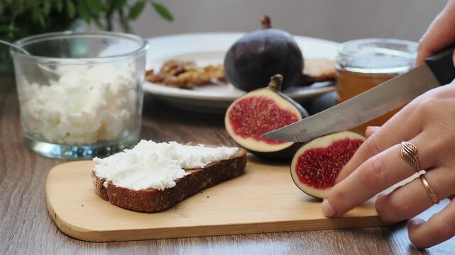 Toasted whole wheat bread with figs, ricotta (cream cheese),mint, honey served on white wooden cutting board. Healthy food concept.