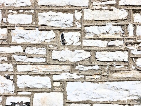 Close-up of a rustic exterior stone wall featuring light-colored ashlar blocks set with distinct dark mortar lines.