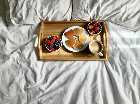 Heart-shaped pancakes and berries on a cozy breakfast tray