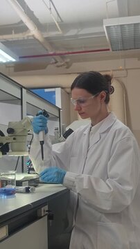 Lab or laboratory. Female scientist conducting laboratory research using lab tools. Such as microscope pipette and laptop to analyze samples and colorful bio chemical solutions in a modern laboratory