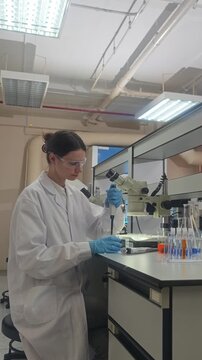Lab or laboratory. Female scientist conducting laboratory research using lab tools. Such as microscope pipette and laptop to analyze samples and colorful bio chemical solutions in a modern laboratory