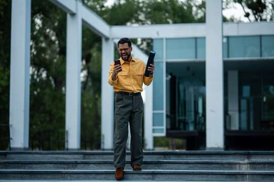 Happy graduate student celebrating success with phone
