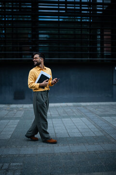 Professional man walking smiling with documents and phone