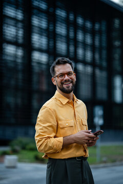 Happy professional man holding smartphone smiling outdoors