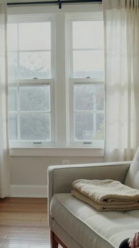 Vertical video: Panning camera right, revealing sash windows at home with fig plant and armchair