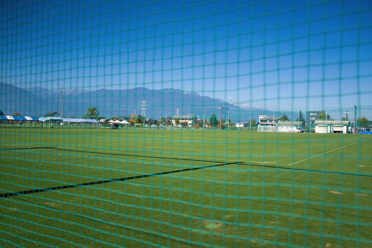 サッカーグラウンドとネット越しの風景