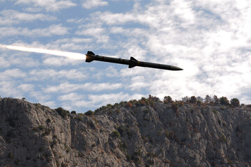 Obraz premium Guided missile flying above rocky cliffs under a cloudy sky