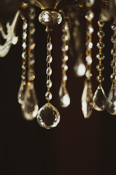 Close-up of elegant crystal chandelier pendant decorations hanging in dark interior.