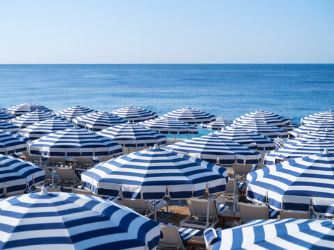 Sun umbrellas and sunbeds on a sandy beach by the sea. Summer vacation and travel resort on a sunny day. A place to rest and relax.