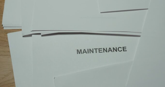 A sheet of paper is pulled away to reveal the word Maintenance underneath.
