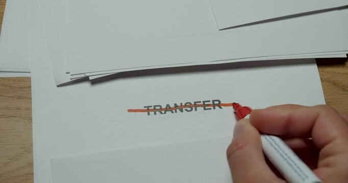 Close-up of the word Transfer being crossed out with a red pen. Concept for cancelled transfer, rejected transaction, relocation cancellation and change of plans.