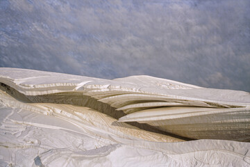 Wind and melt have carved glacier ice into flowing cream coloured layers that curve like folded fabric © Kafi