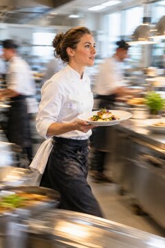 Waitress Carrying Dish Through Kitchen