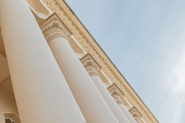 Architectural facade featuring a colonnade with detailed floral capitals and entablature on a cream-colored building. © tatiana
